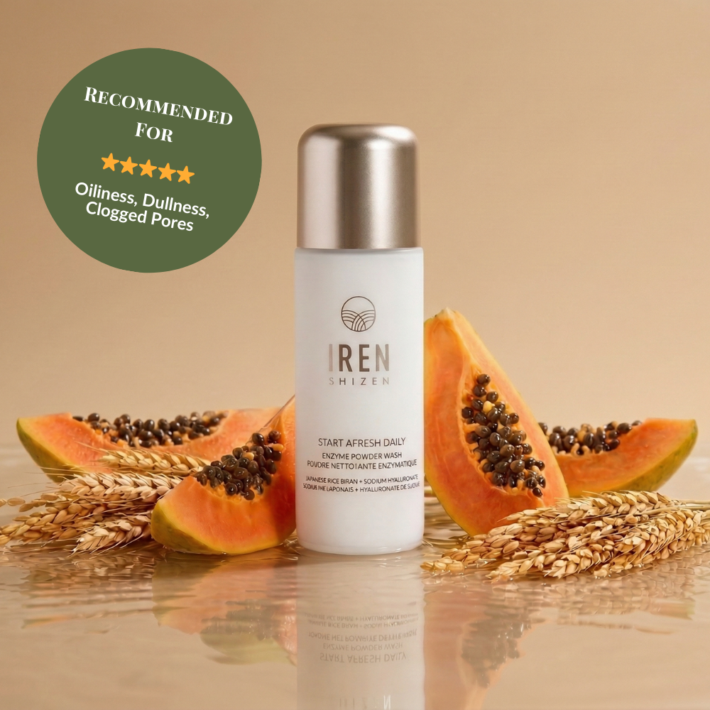 A bottle of START AFRESH DAILY Enzyme Powder Wash by IREN Shizen, a gentle daily exfoliator, is shown with papaya slices and wheat stalks, featuring a green badge recommending it for oiliness, dullness, and clogged pores.