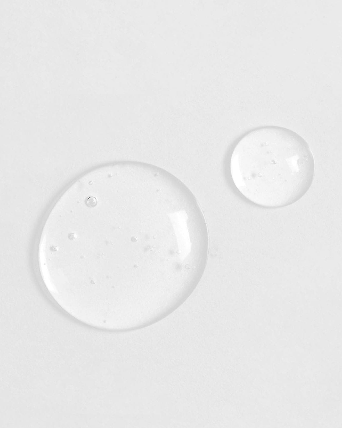 Two Japanese QUENCH-UP Hydrating Serum drops on a white surface.