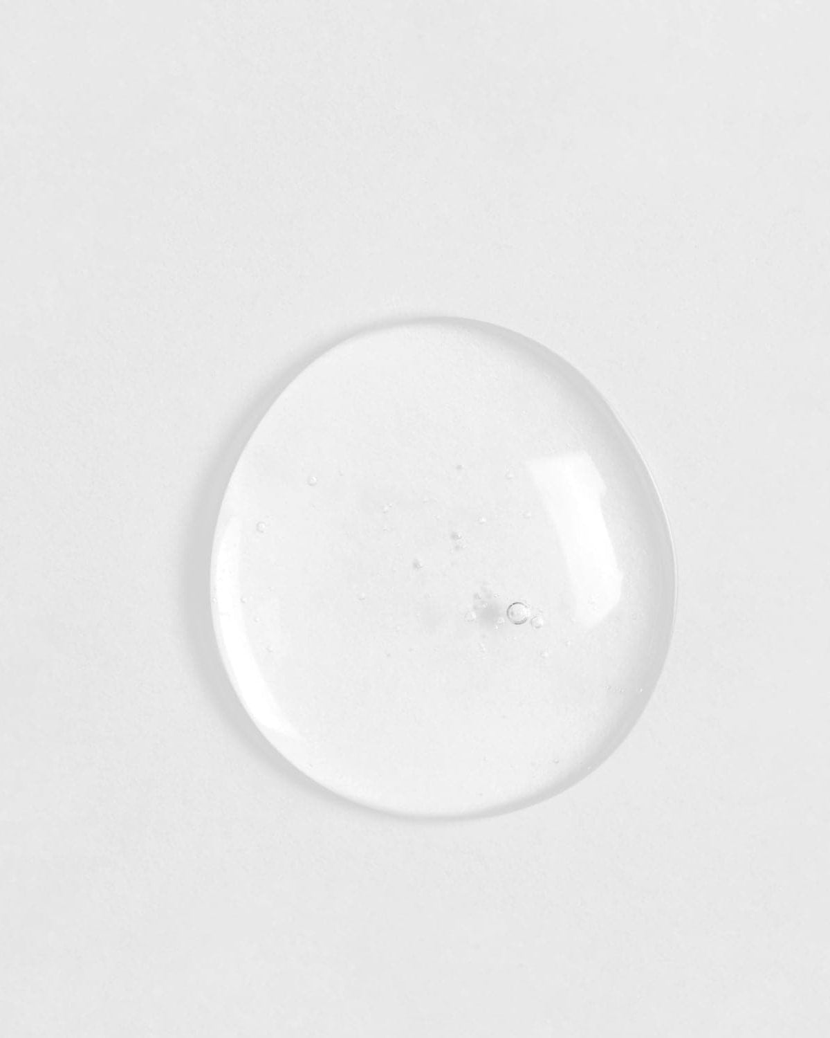 A clear glass ball of customised SKIN REBOOT Antioxidant Serum on a white surface by IREN Shizen.