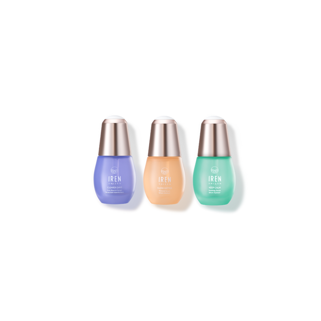 Three skincare serum bottles from IREN Shizen, including the CLEAR UP Anti-Blemish Set with purple, beige, and green colors, against a white background.
