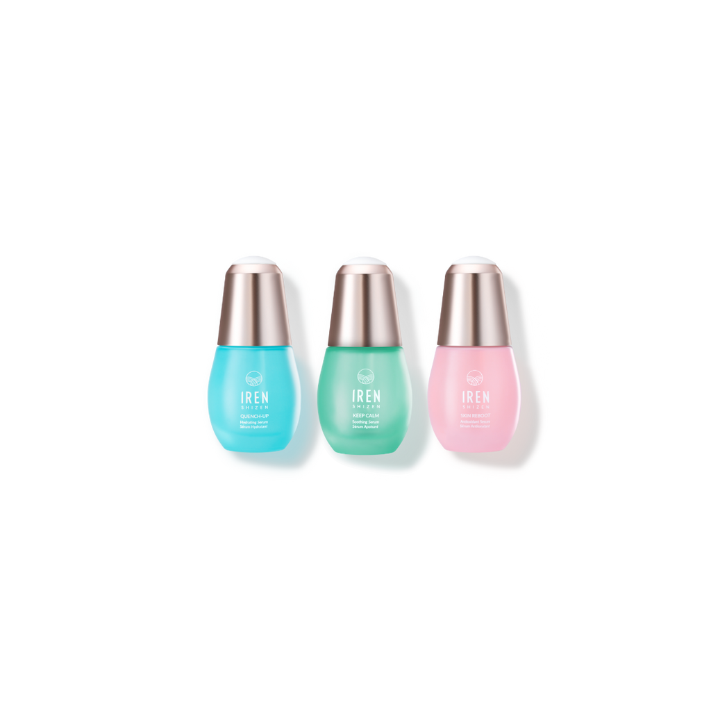 Three DEW UP Hydrating Set bottles in blue, green, and pink, aligned side by side, each with silver caps. This IREN Shizen set includes soothing serums rich in antioxidants.