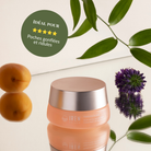 A jar of IREN Shizen TIMELESS ELIXIR Multi-Lift Eye and Lip Cream sits on a reflective surface with green leaves, a purple flower, and two orange fruits. A badge highlights its benefits for puffiness, dark circles, and fine lines.
